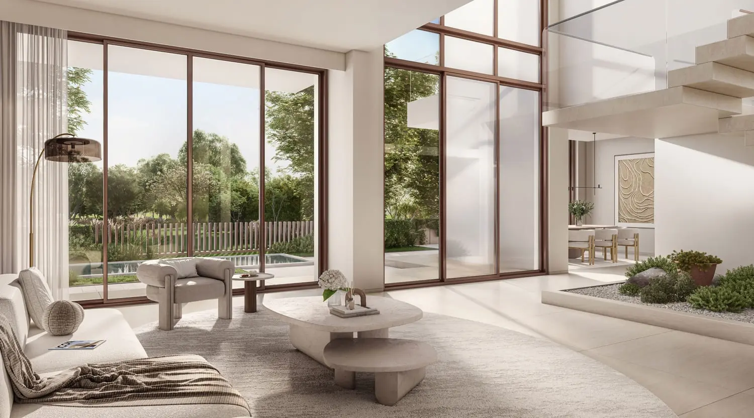 Double-height living room framing garden and pool views at Bayn by Ora, Ghantoot, between Abu Dhabi and Dubai